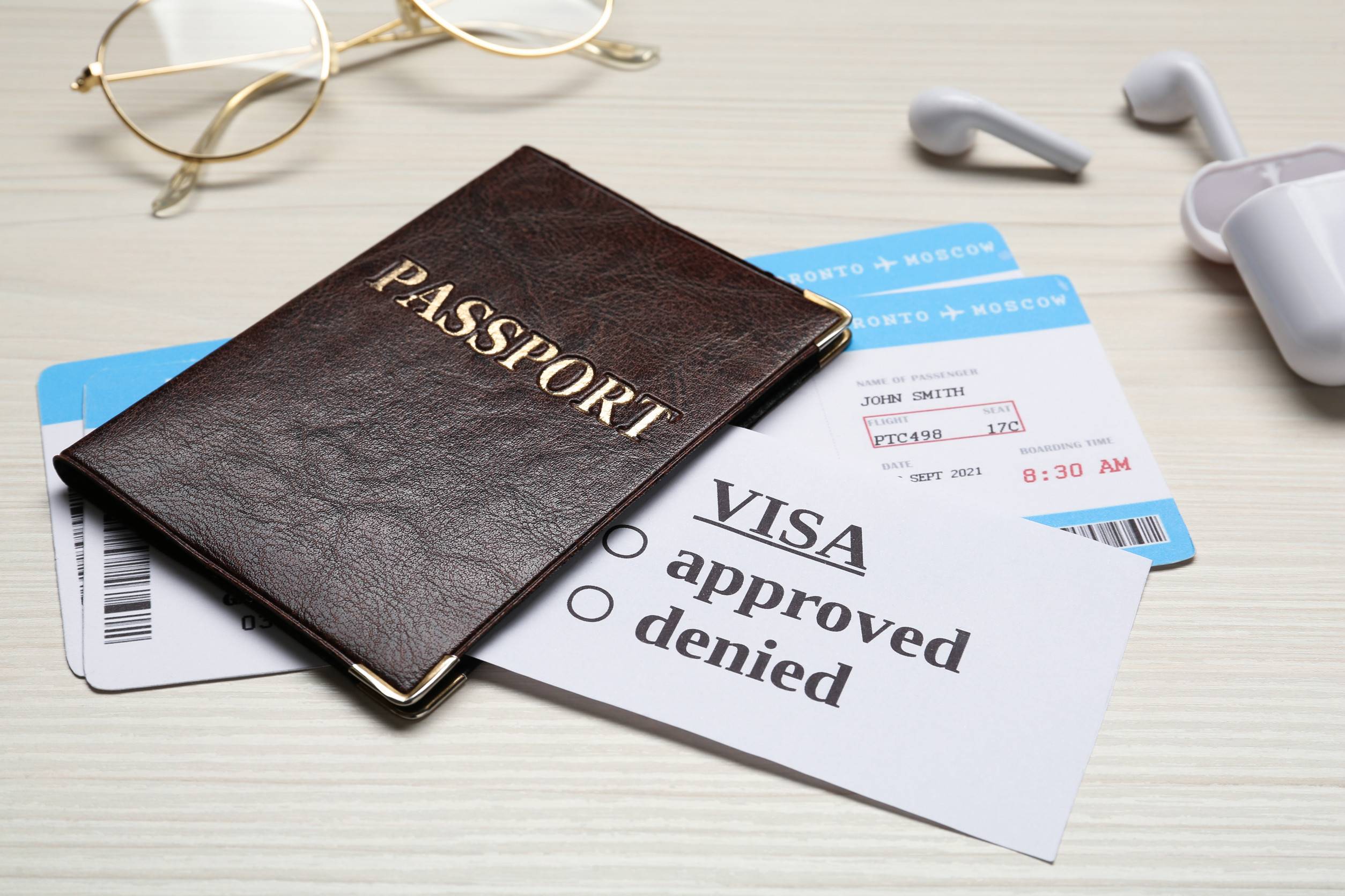 Passport Tickets Earphones And Glasses On White Wooden Table